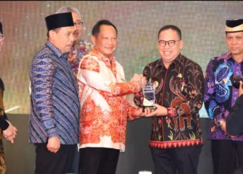 Makmur Marbun (kanan) saat menerima penghargaan dari Menteri Dalam Negeri, Muhammad Tito Karnavian. (foto : istimewa)