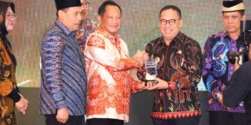 Makmur Marbun (kanan) saat menerima penghargaan dari Menteri Dalam Negeri, Muhammad Tito Karnavian. (foto : istimewa)