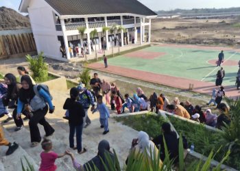Sejumlah orang tua mendampingi anak-anak melewati jalan tanah dan tangga menuju SDN 022 Balikpapan Timur pada hari pertama masuk sekolah, Senin (13/7/2026).